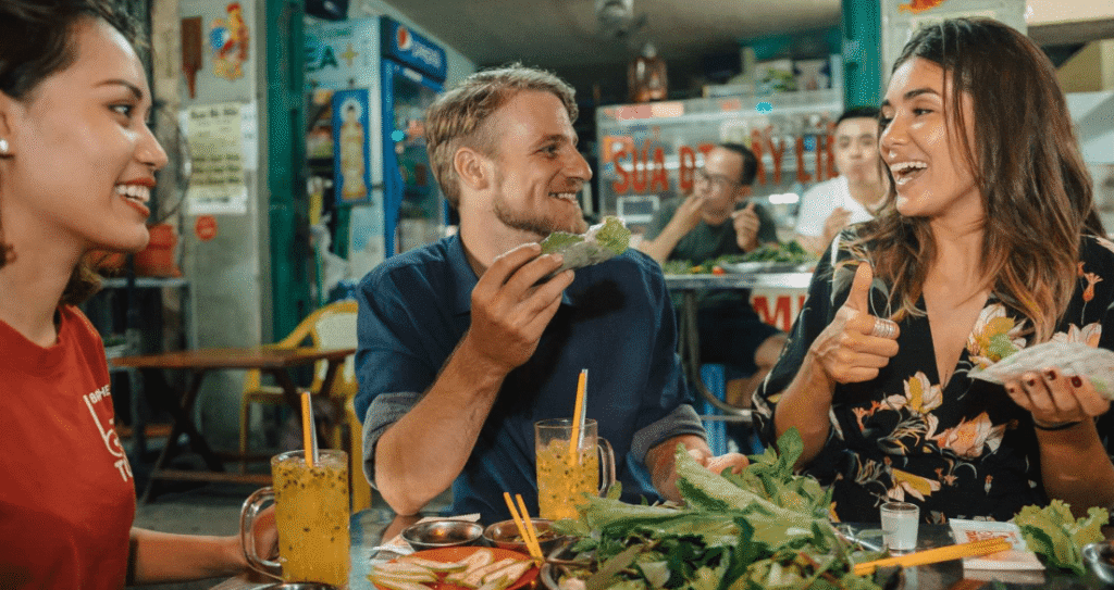 Guests tasting goi cuon, traditional Vietnamese fresh spring rolls, on a Saigon food tour.