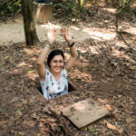 Visitor experiencing crawling into a hidden trapdoor of the Cu Chi Tunnels.