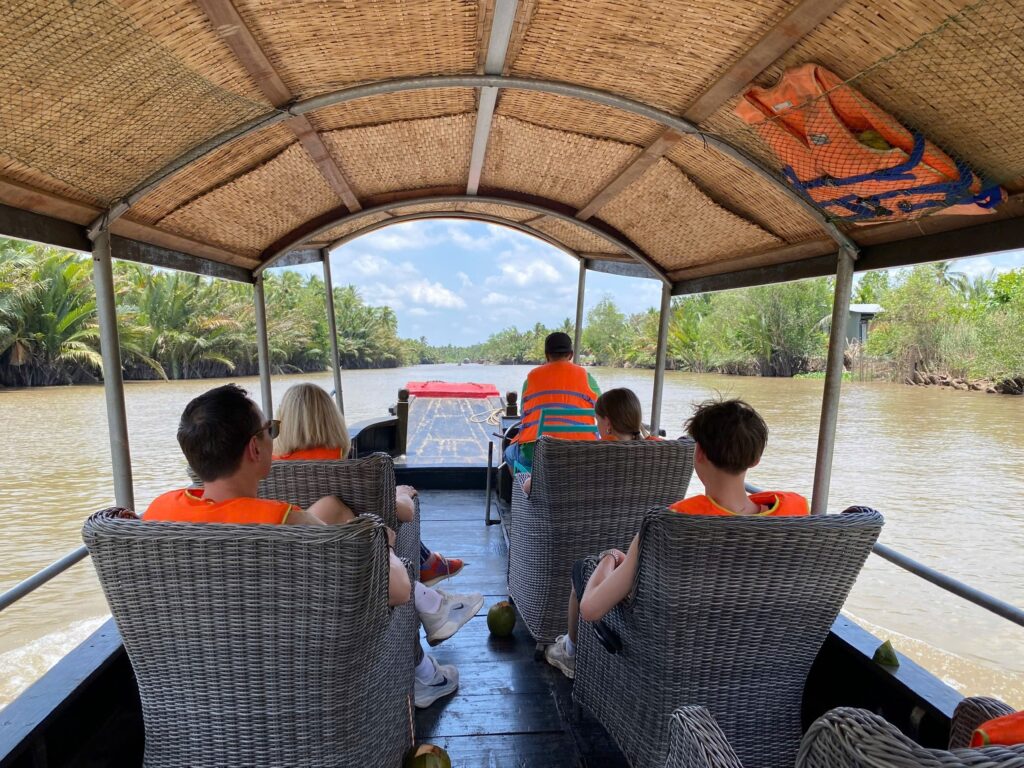 Tourists are sitting on a sampan boat cruising along the river in the Mekong Delta.