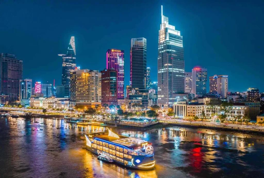 Cruise sailing along Saigon River at night under the city’s colorful lights.