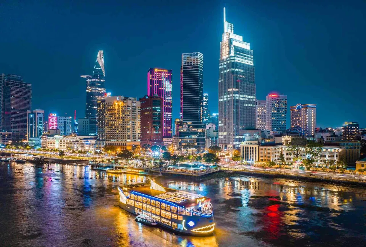Cruise sailing along Saigon River at night under the city’s colorful lights.