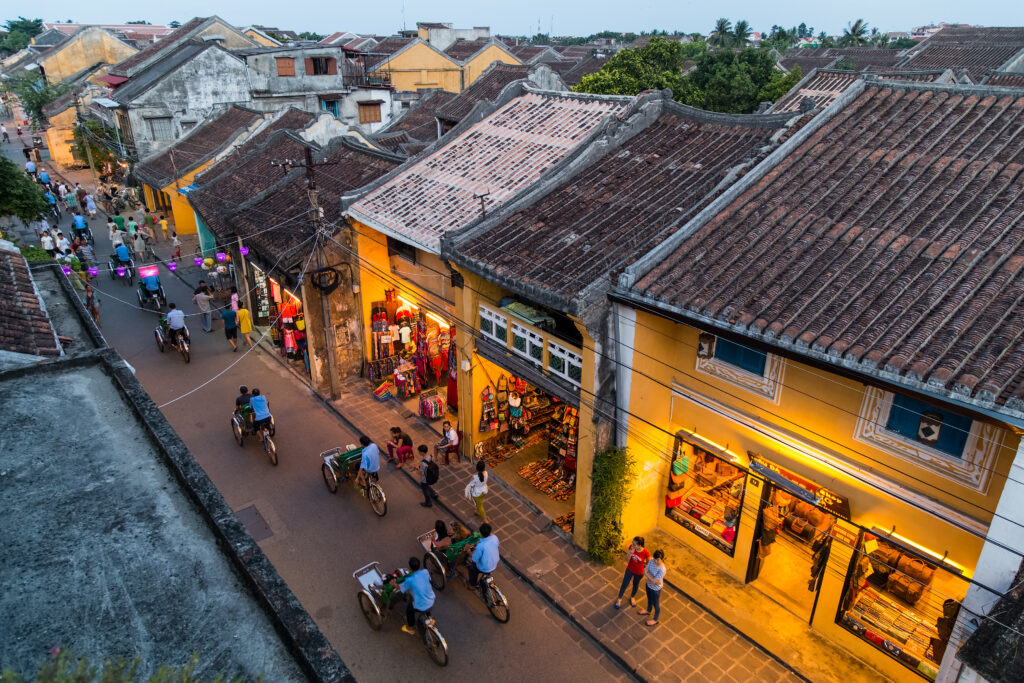 The ancient town of Hoi An, viewed from above, reveals many people riding cyclo rickshaws.