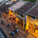 The ancient town of Hoi An, viewed from above, reveals many people riding cyclo rickshaws.