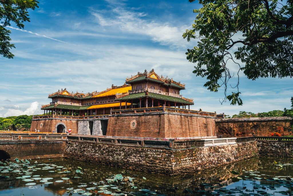 Side view of the Imperial City of Hue photographed from below, overlooking calm water and historic architecture.
