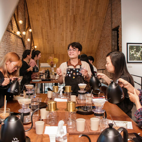 A local host smiling while guiding guests in a morning coffee workshop in Saigon, sharing traditional Vietnamese coffee culture.