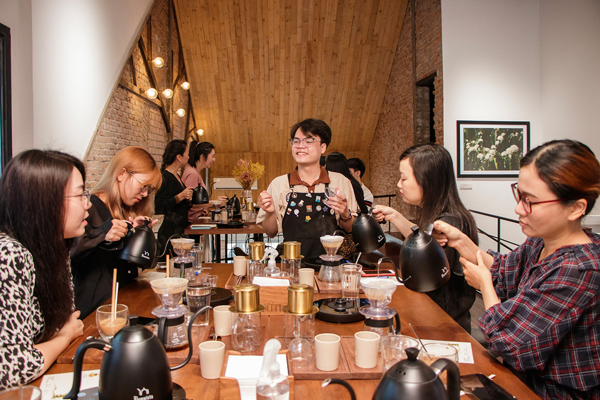 A local host smiling while guiding guests in a morning coffee workshop in Saigon, sharing traditional Vietnamese coffee culture.