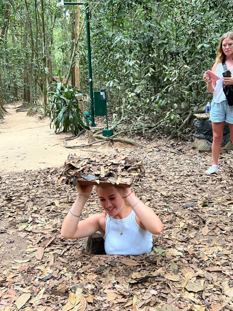 A girl is crawling into a tunnel in Cu Chi.