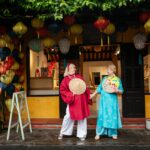 2 women tourists wearing a traditional ao dai in hoi an, viet nam