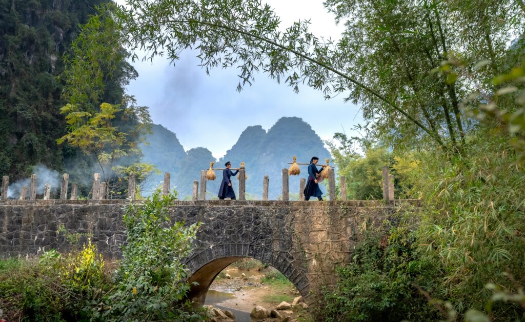 2 local women passing through rice field and mountain scenic