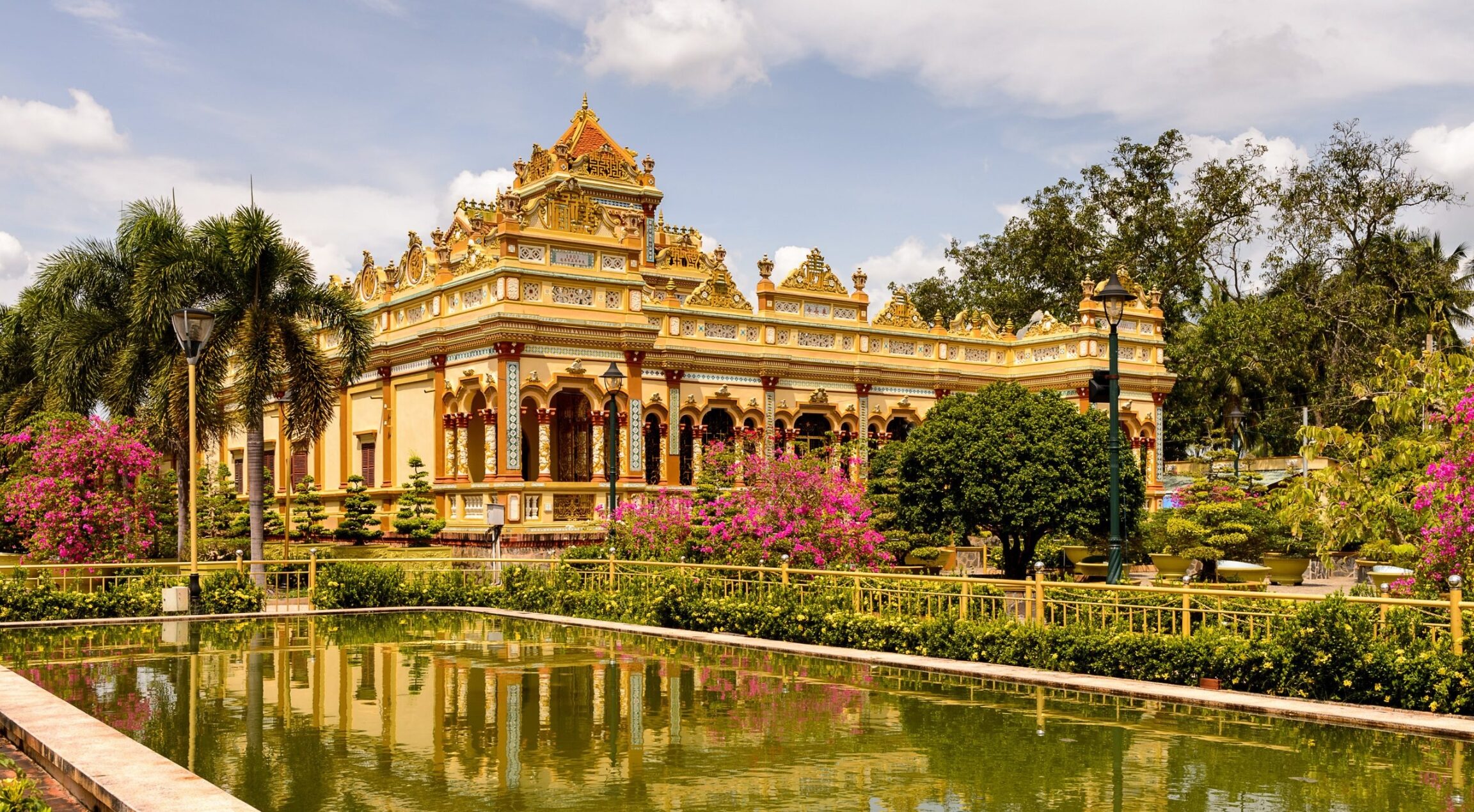 Golden Vinh Trang Pagoda in My Tho seen from the side, reflected peacefully on the temple pond.