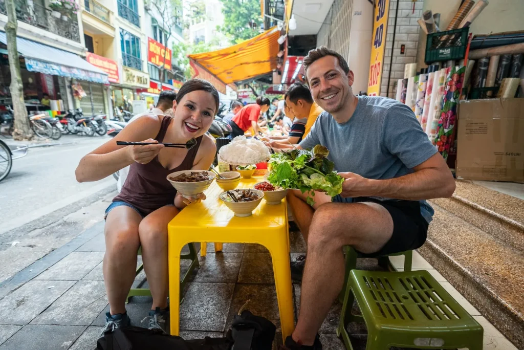 a couple trying hanoi street food
