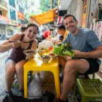a couple trying hanoi street food